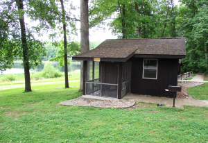 A small park building with trees and water in the background